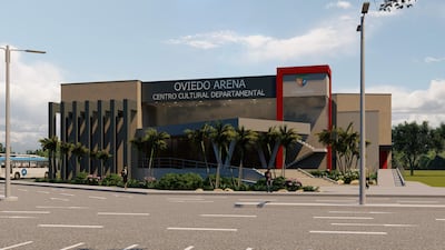 Exterior del moderno Oviedo Arena con estacionamiento vacío y cartel visible, rodeado de plantas y cielo despejado.