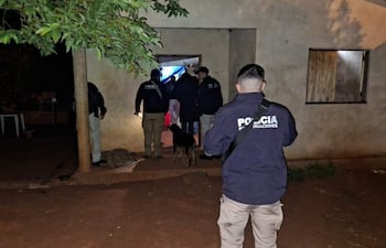 Agentes de policía con chaquetas oscuras y perro de trabajo en una noche oscura en frente de una construcción.