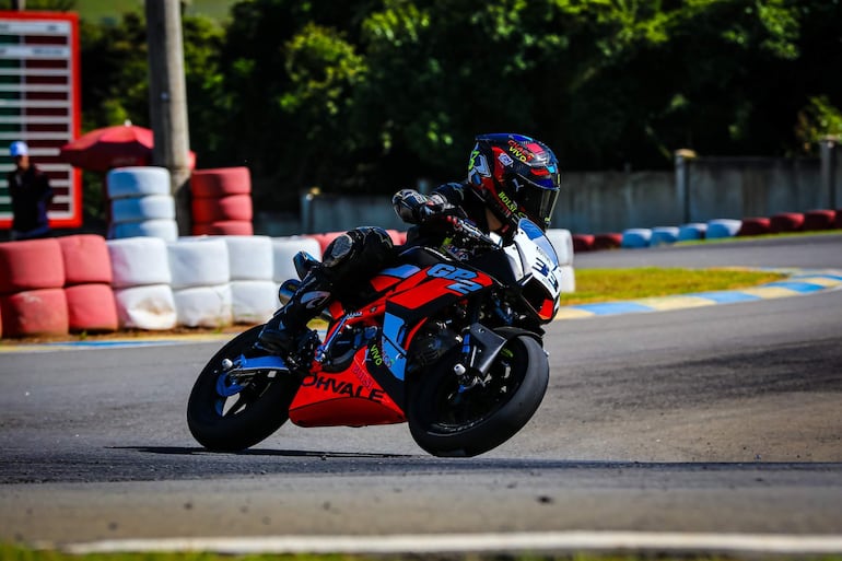 Piloto en traje negro y casco colorido con número 33, controlando la motocicleta en curva, pista de karting en ambiente exterior.