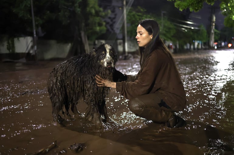 Una mujer sostiene a su perro afectado por un aluvión este jueves, en la comuna de Las Condes, en Santiago (Chile).