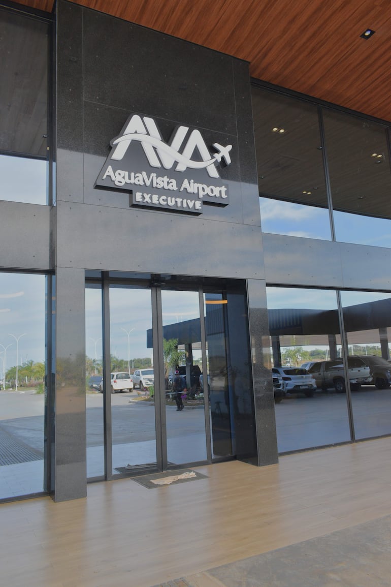 Entrada del Aeropuerto Ejecutivo Aguavista con letrero visible y área de estacionamiento desierta.