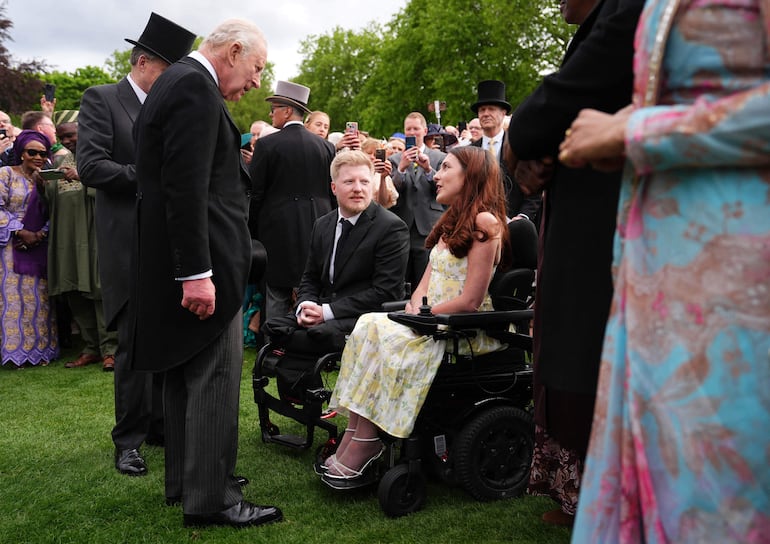 Carlos III conversa con antiguos ganadores del Premio del Rey al Servicio Voluntario (KAVS) durante una fiesta en los jardines del Palacio de Buckingham. (Aaron Chown / POOL / AFP)
