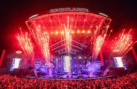 Multitud anónima en concierto al aire libre, con escenario iluminado y fuegos artificiales en el fondo durante el Reciclarte 2026.