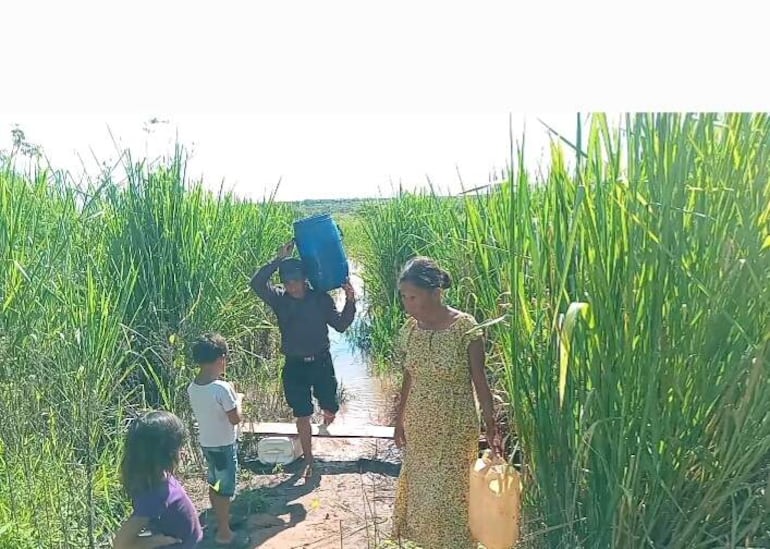 La gente del asentamiento toman agua del cauce del río Capiibary que actualmente se encuentra extremadamente sucia tras las intensas lluvias.