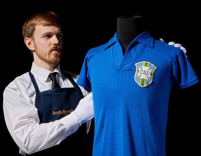Fotografía tomada de la cuenta en X @Sothebys de la casa de subastas Sotheby's que muestra a una persona exhibiendo la camiseta que el futbolista brasileño Pelé llevó en la final del Mundial de 1958 y que se estima será subastada en 6 millones de dólares en julio en Nueva York (EE.UU.).