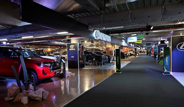 Vehículos Toyota en exhibición, con un modelo rojo destacado, decorado con cactus y elementos de marca en un ambiente moderno.