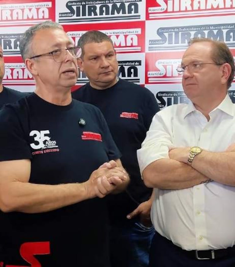 Camilo Pérez con camiseta negra gesticulando en reunión sindical, mientras otros asistentes lo observan, entorno con referencias a SITRAM.
