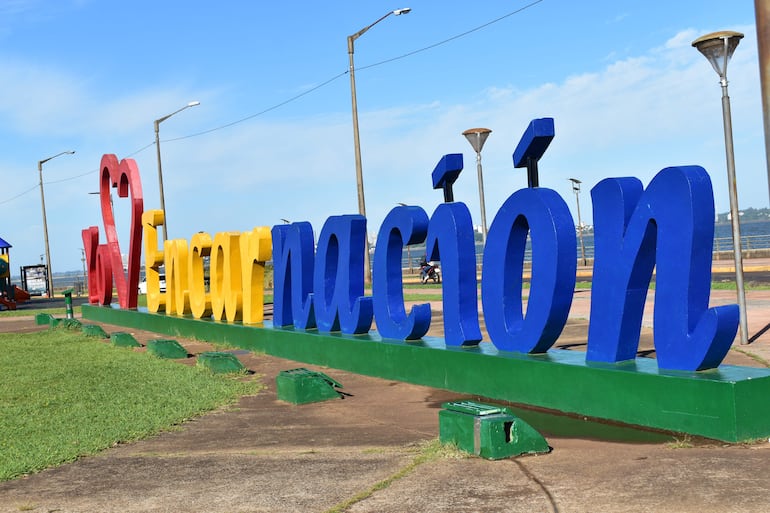 Letrero 'I ❤️ Encarnación' en colores vibrantes, destaca en un parque con césped y estructuras de juegos al fondo.