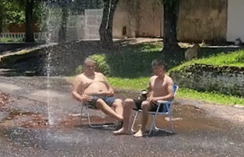 Un señor y aparentemente su hijo, aprovechando "el manantial" de un caño roto de Essap.