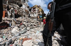 Un hombre armado monta guardia mientras una excavadora retira los escombros de un edificio parcialmente destruido por un ataque aéreo israelí, durante una visita de prensa organizada por la oficina de prensa de Hezbolá, en el barrio de Hay el-Sellom, en las afueras del sur de Beirut, Líbano, el 10 de abril de 2026.