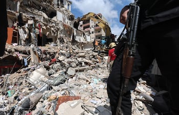 Un hombre armado monta guardia mientras una excavadora retira los escombros de un edificio parcialmente destruido por un ataque aéreo israelí, durante una visita de prensa organizada por la oficina de prensa de Hezbolá, en el barrio de Hay el-Sellom, en las afueras del sur de Beirut, Líbano, el 10 de abril de 2026.