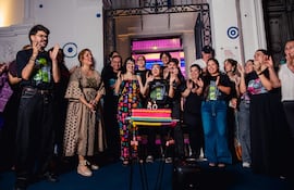 Celebrantes sonrientes en evento del Centro Cultural, con pastel '50', en ambiente festivo y decorado.