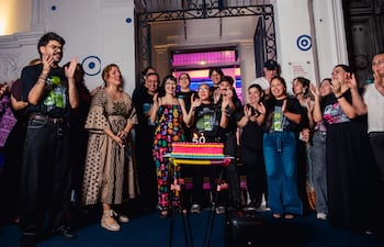 Celebrantes sonrientes en evento del Centro Cultural, con pastel '50', en ambiente festivo y decorado.