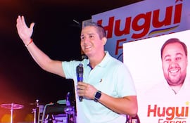 Hugo Carlac, con camiseta celeste, sostiene un micrófono mientras saluda a la audiencia en un ambiente festivo.