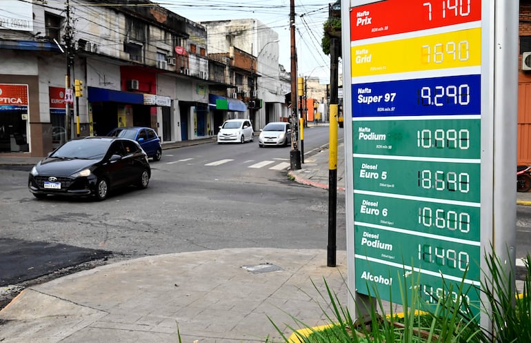 Cartel con precios de combustibles en estación Petrobras, rodeada de vehículos en una calle urbana.