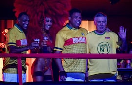 El entrenador italiano de la selección brasileña de fútbol, Carlo Ancelotti (der.), saluda junto a los exfutbolistas Ronaldo (centro-der.) y Denílson, y la presentadora de televisión brasileña Sabrina Sato, sobre una carroza de la escuela de samba Acadêmicos de Niterói antes de la noche inaugural del Carnaval de Río en el Sambódromo Marqués de Sapucaí en Río de Janeiro, Brasil.