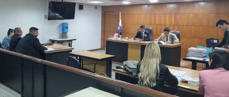 Sala de audiencia con jueces Manuel Aguirre y Juan Ortiz. Cuatro personas vestidas formalmente sentadas frente a ellos.