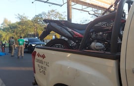 En el pavimento, la víctima fatal tras ser arrollado por un motociclista, cuyo biciclo se ve en la carrocería de una patrullera de la Policía Nacional.