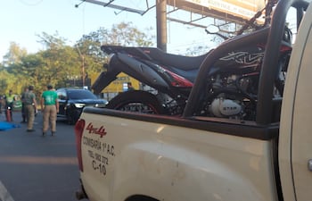 En el pavimento, la víctima fatal tras ser arrollado por un motociclista, cuyo biciclo se ve en la carrocería de una patrullera de la Policía Nacional.