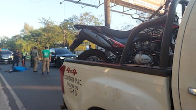 En el pavimento, la víctima fatal tras ser arrollado por un motociclista, cuyo biciclo se ve en la carrocería de una patrullera de la Policía Nacional.