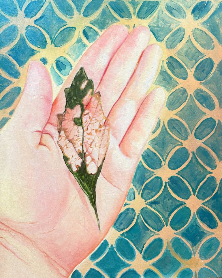 Hoja verde y marchita sostenida por una mano clara, sobre fondo decorativo azul y amarillo.