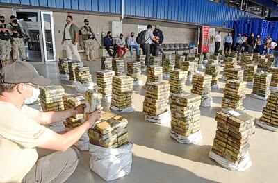 Los antidrogas acomodan los paquetes de la droga prensada que estaban ocultos en bolsas cargadas con carbón vegetal.