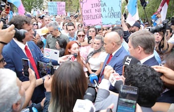 Marcelo Javier Soto Pavón en traje azul y corbata roja, Lizarella Valiente Cabrera con micrófono y otros manifestantes sosteniendo carteles en una plaza.