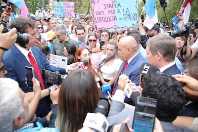 Marcelo Javier Soto Pavón en traje azul y corbata roja, Lizarella Valiente Cabrera con micrófono y otros manifestantes sosteniendo carteles en una plaza.