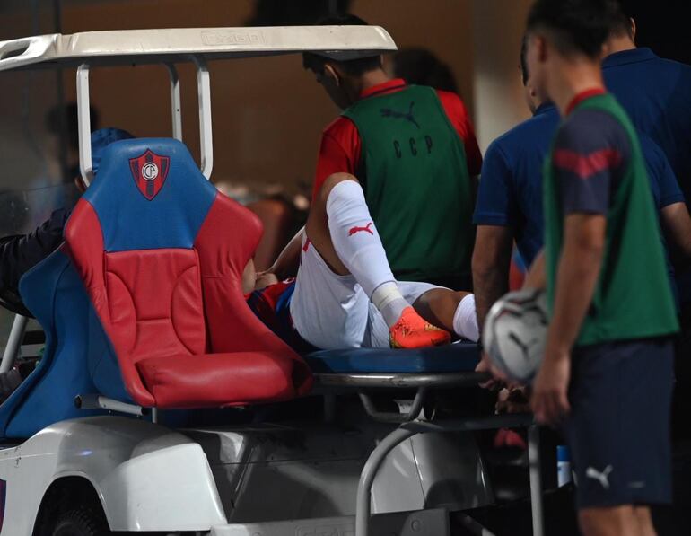 El jugador Víctor Cabañas, en el camillero móvil, durante la salida del campo a causa de la lesión que sufrió en la pierna izquierda en el partido contra Libertad por la penúltima jornada del torneo Apertura 2023 del fútbol paraguayo en La Nueva Olla, Asunción.