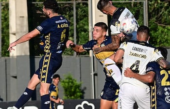 El lateral Alex Cañete (6), del Triqui, en el duelo aéreo por la pelota con el central aurinegro Sebastián Zaracho (4) y otros.
