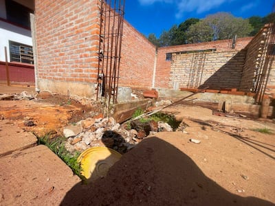 Espacio en construcción sin personas visibles, con muros de ladrillo rojo y escombros acumulados en el suelo.
