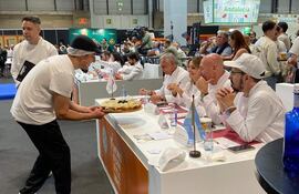 Grupo en evento culinario con chef sirviendo un plato gourmet a comensales atentos en un ambiente profesional.