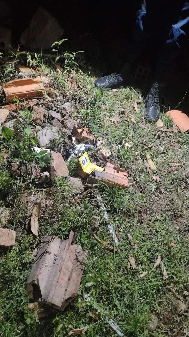 Escena del crimen en la noche, con marcador amarillo número 01 y restos de objetos en el suelo.