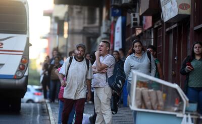 Un pasajero bosteza mientras espera el bus, junto a más usuarios del sistema. La gente está visiblemente cansada de las reguladas.
