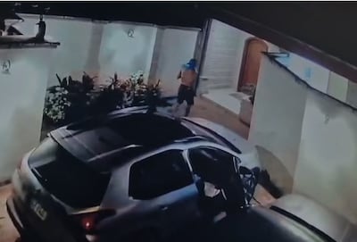 El maleante comienza a acomodar sobre la muralla de la casa, todo los objetos encontrados en el interior de uno de los vehículos, para poder sacarlos de la propiedad con más facilidad.