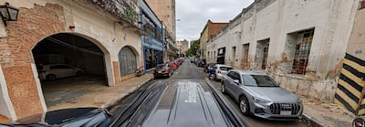 Calle urbana con edificios de ladrillo y vehículos estacionados bajo un cielo nublado.