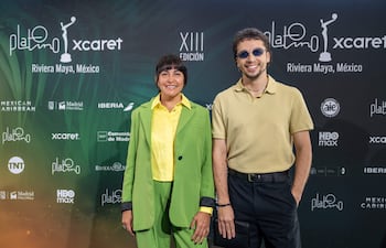 Dolores Giménez con traje verde brillante y blusa amarilla, junto a Marcos Cáceres en camiseta amarilla y pantalones negros, sonriendo en evento.