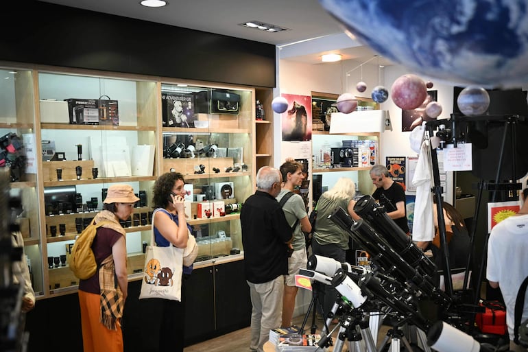 Clientes hacen fila en la caja de una óptica especializada en optometría comportamental para comprar gafas de observación de eclipses solares, en París, el 11 de agosto de 2026, en vísperas de un eclipse solar parcial.