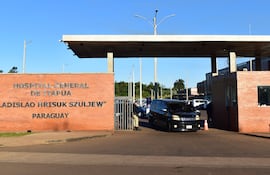 Guardia de seguridad junto a la reja del Hospital General de Itapúa, controlando un vehículo negro en un entorno ordenado.