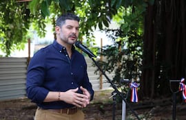 Oscar Andrés Rodríguez Quiñonez en camisa azul oscuro gesticulando frente a un micrófono, rodeado de vegetación.