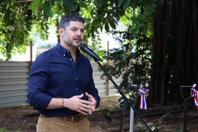 Oscar Andrés Rodríguez Quiñonez en camisa azul oscuro gesticulando frente a un micrófono, rodeado de vegetación.
