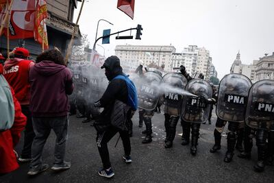 Policías lanzan agua durante enfrentamientos entre la policía y personas que protestan a las afueras del Senado durante un debate este miércoles, en Buenos Aires (Argentina).
