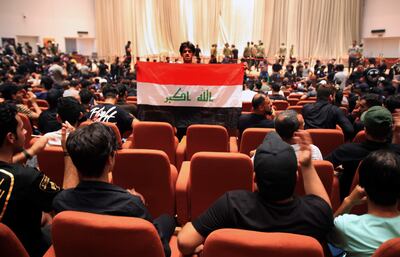 Un simpatizante del clérigo chiíta iraquí Muqtada al-Sadr, jefe del movimiento Sadrista, lleva la bandera nacional iraquí dentro del salón del parlamento iraquí en el centro de Bagdad, Ira.