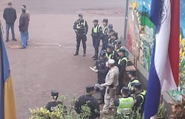 Grupo de policías en la calle, con chalecos verdes y gorras, mientras un hombre en uniforme camuflado da instrucciones en el centro.