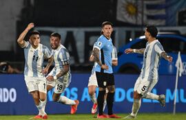 Argentina's midfielder #11 Thiago Almada celebrates with teammates defender #19 Nicolas Otamendi and midfielder #05 Leandro Paredes after scoring during the 2026 FIFA World Cup South American qualifiers football match between Uruguay and Argentina at the Centenario stadium in Montevideo, on March 21, 2025. (Photo by Eitan ABRAMOVICH / AFP)