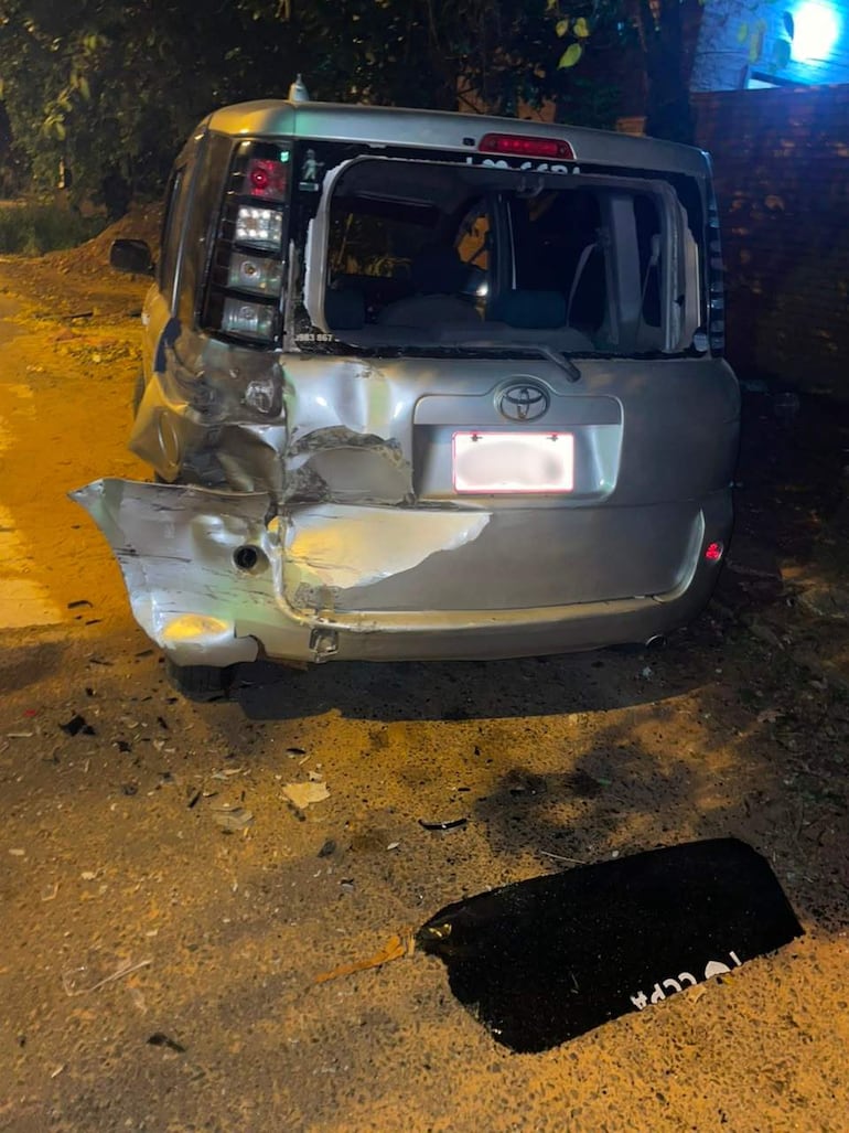 Automóvil Toyota dañado con parte trasera rota y abollada, en una calle oscura sin ocupantes presentes.