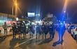 Seis policías en uniforme alineados, equipados con escudos, en una calle urbana iluminada de Encarnación.