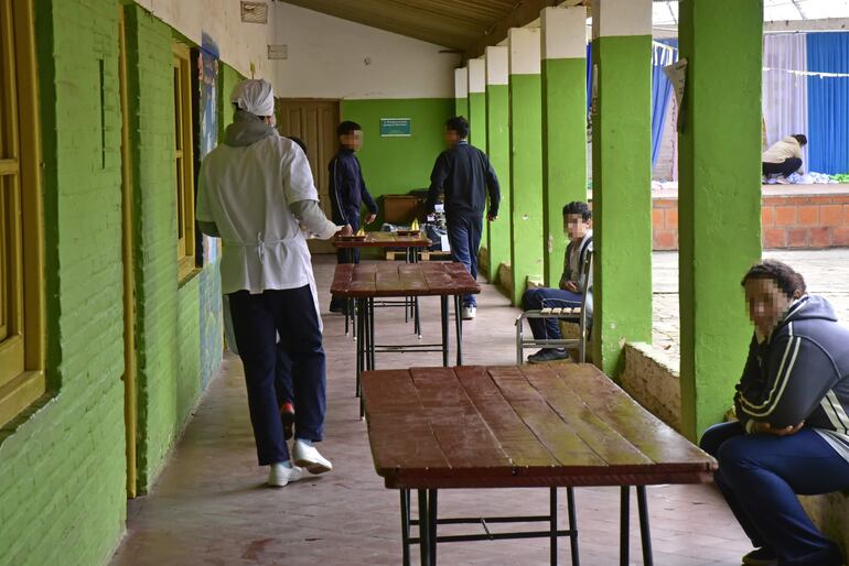 Estudiantes almuerzan con tablones en un pasillo en una escuela de Lambaré.
