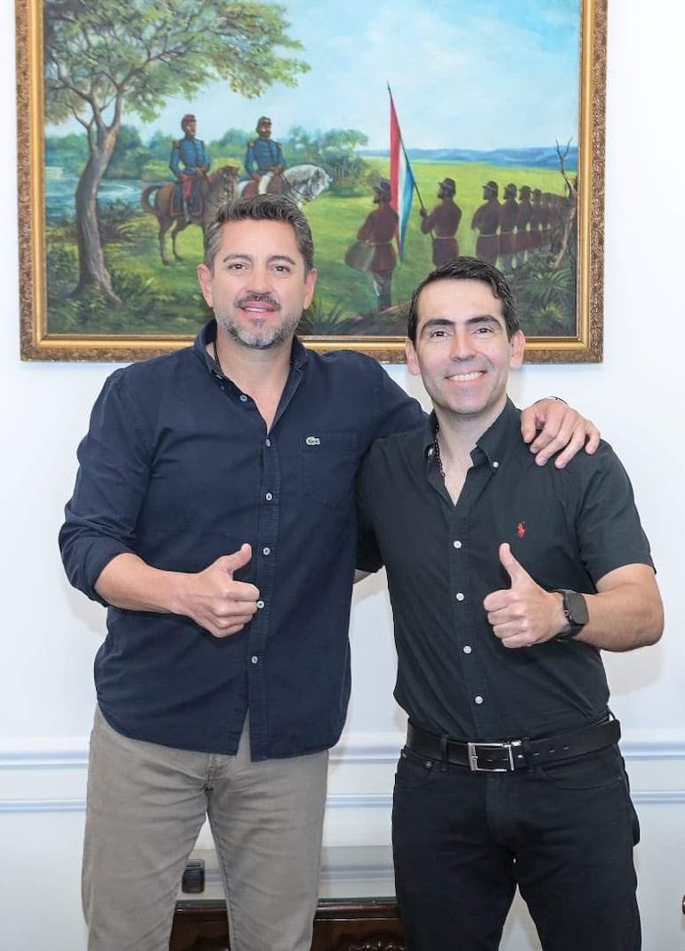 Pedro Alliana en camisa azul oscura y Marcelo Javier Soto Pavón en camisa negra, ambos sonrientes y mostrando el pulgar hacia arriba en un ambiente de oficina.