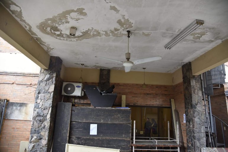 Espacio interior deteriorado con ventilador de techo y unidad de aire acondicionado montada, sin personas presentes.